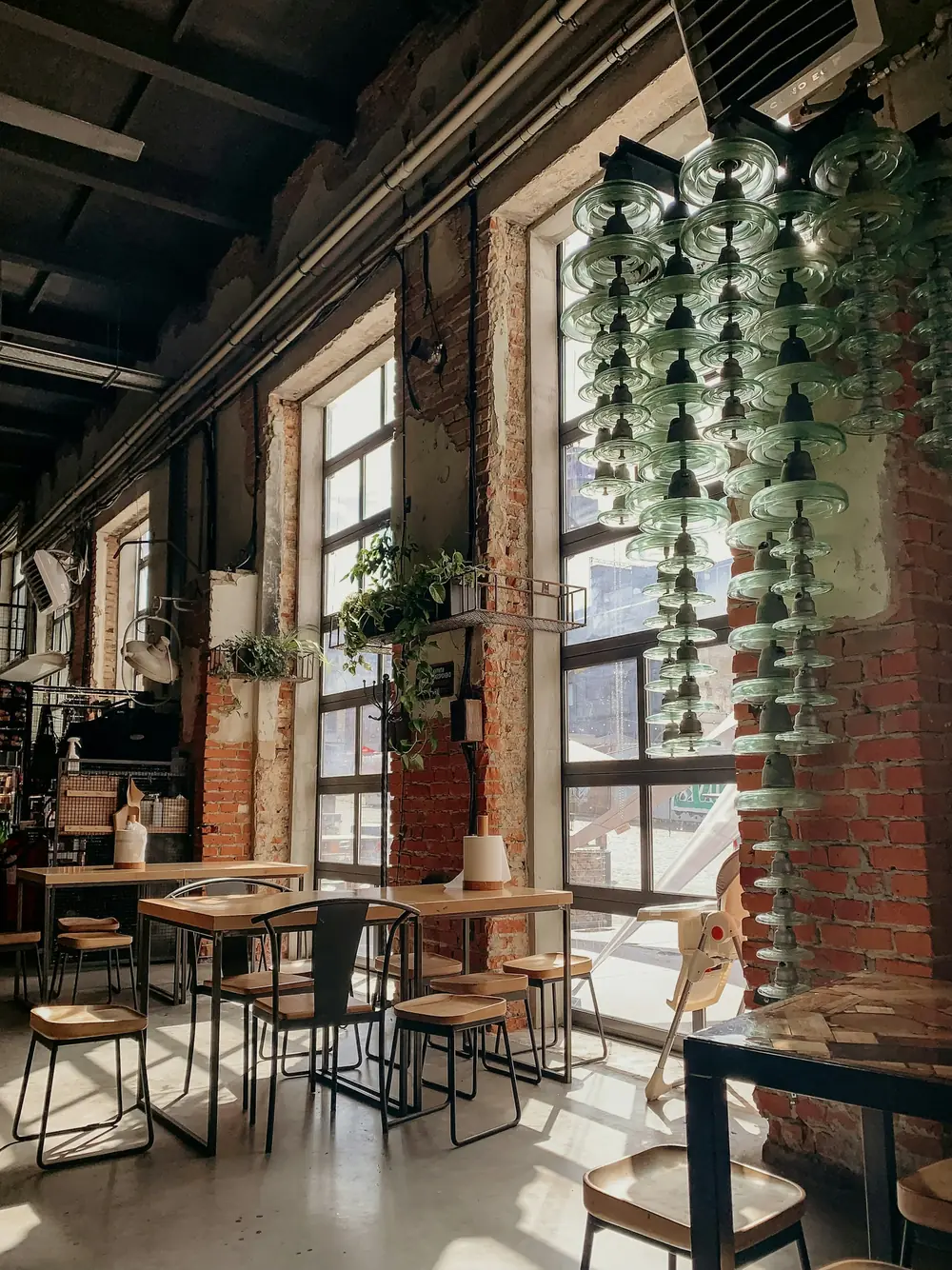 Het café met hoge ramen, bakstenen muren en hangende planten