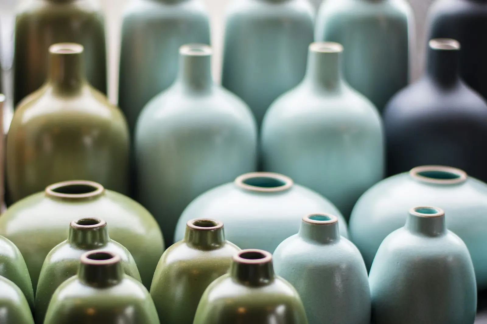 Rijen geglazuurde vazen in groen, blauwgrijs en zwart